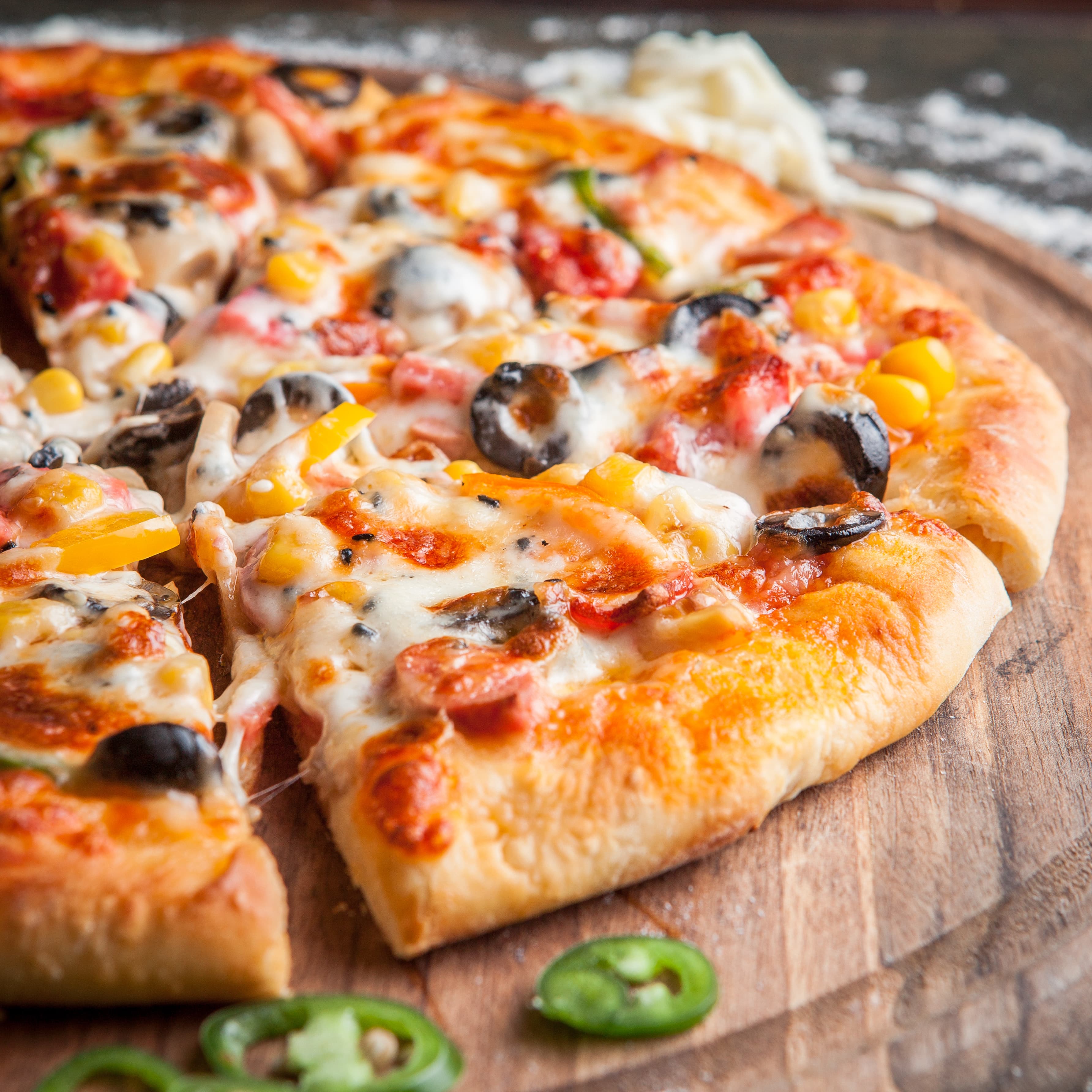 Gros plan sur une pizza généreusement garnie, pâte filante